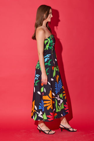 Woman wearing a strapless dress with colorful leaf pattern against a red background