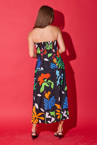 Woman wearing a strapless dress with colorful floral pattern against a red background